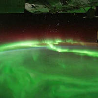 a photograph of green auroras over the Earth